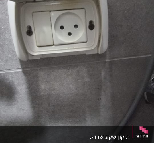 שקע חשמל עם כיסוי פתוח על קיר אפור